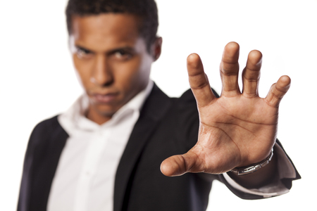 angry dark-skinned guy showing stop with his handの写真素材