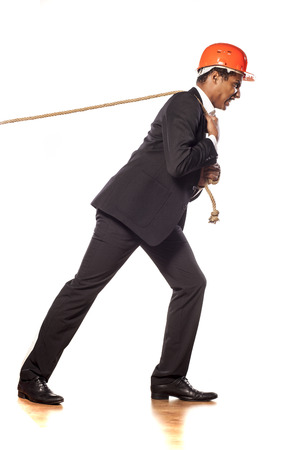 African businessman with a helmet pulling a ropeの写真素材