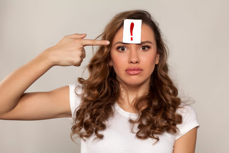 astonished girl with an exclamation mark drawn on a paper over her forehead