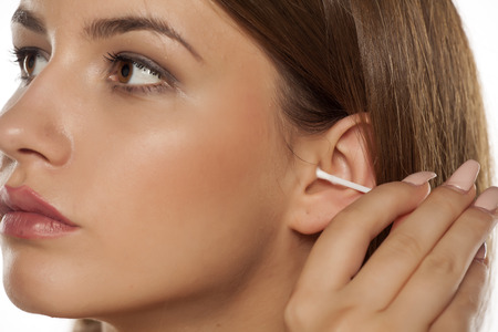 woman cleaning her ear using cotton swabの写真素材