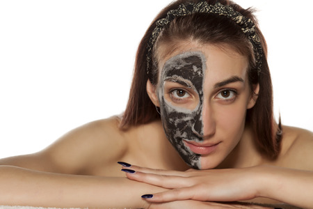 young woman with mud mask on half of her faceの写真素材