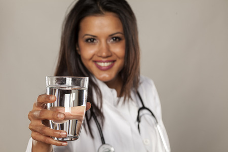 Smiling woman doctor holding a glass of waterの写真素材