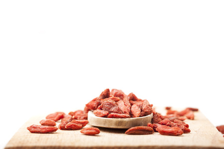 pile of dried goji berries on a wooden spoon on a white backgroundの写真素材