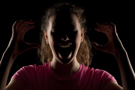 screaming unknown woman with the face in the shadowの写真素材
