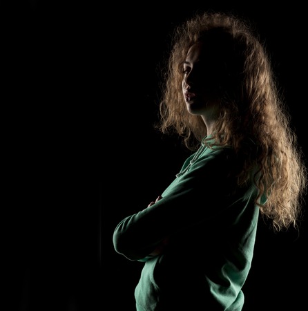 portrait of a girl with the face in shadow on a dark backgroundの写真素材