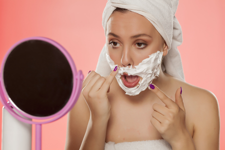 beautiful young woman applied shaving cream on her faceの写真素材