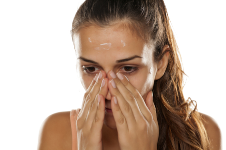 young beautiful woman applied protective cream on her faceの写真素材