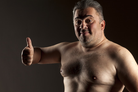 a fat shirtless man shows thumbs upの写真素材