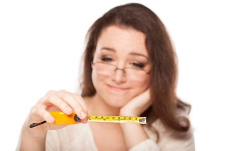 A young woman is pensive at the size shown on the measuring tape