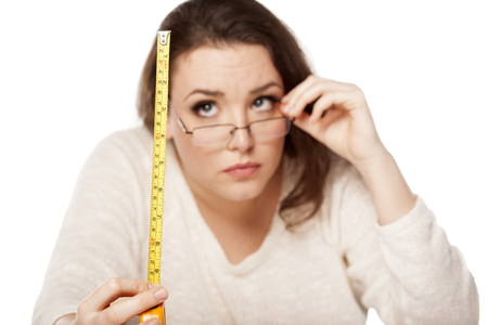 young woman is scared by the size shown on the measuring tapeの写真素材