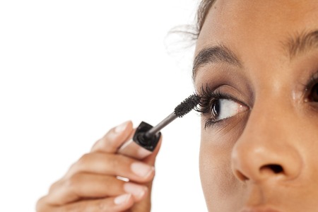 a young dark skinned woman applying a mascara to her eyelashesの写真素材