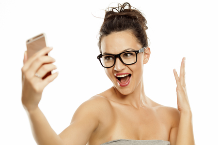 young beautiful woman takes selfies on white backgroundの写真素材