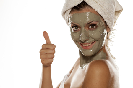 young woman with a towel on her head posing with a mask from green clay on her faceの写真素材