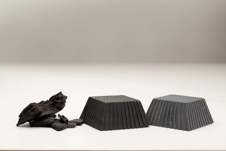 two hand made black soap from activated carbon on white backgroundの写真素材
