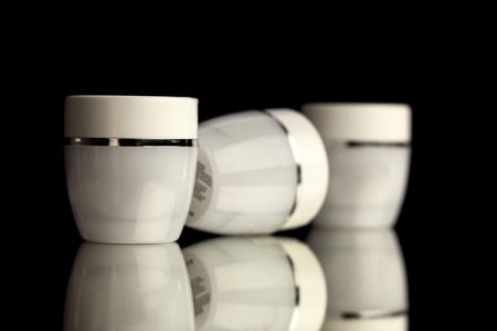 A grup of blank white jars for cosmetics on black backgroundの写真素材