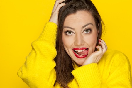 beautiful sexy woman sticking her toungue in a yellow blouse on a yellow backgroundの写真素材