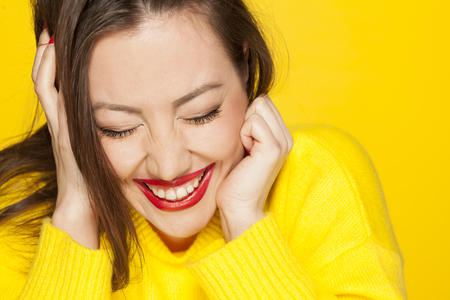 beautiful happy woman in a yellow sweater on a yellow backgroundの写真素材