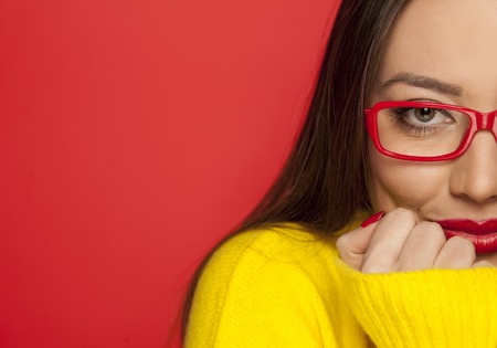 half portrait of beautiful woman with red glasses on red backgroundの写真素材