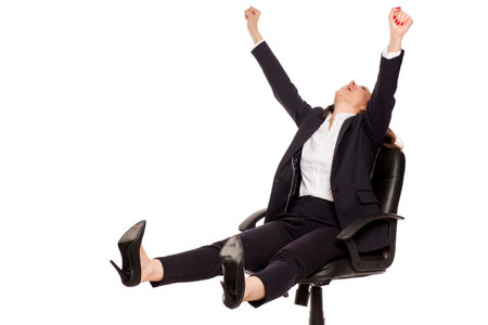happy businesswoman with winning gesture in armchair on white backgroundの写真素材