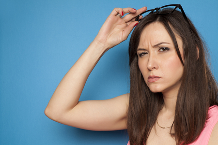 young woman looks suspiciously on a blue backgroundの写真素材