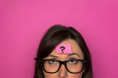 Puzzled young woman with question mark on her foreeadの写真素材