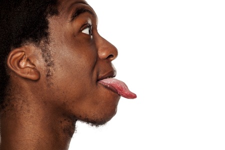 Profile tongue out closeup of young black african american guy on white backgroundの写真素材