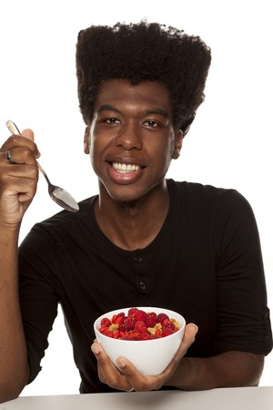 young handsome afro american guy hipster eating cereals woth fresh fruits isolated on white background. healthy food conceptの写真素材