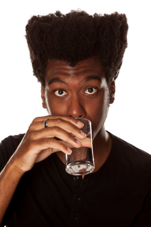 Portrait of young african american man drinking water from a glass  on white backgroundの写真素材