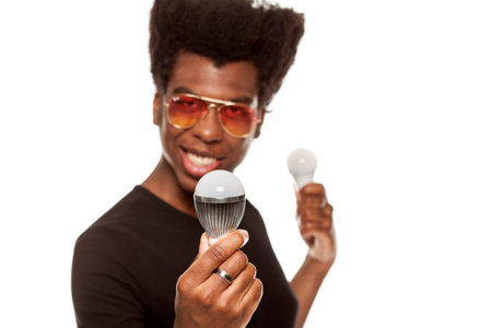 young handsome afro american guy holding LED bulbs isolated on white background. saving energy...