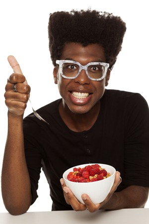 young handsome afro american guy hipster eating cereals woth fresh fruits isolated on white background. healthy food conceptの写真素材