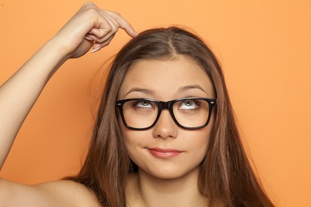 young pensive girl scratching her head with fingerの写真素材