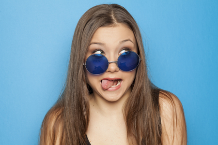 young funny girl with blue sunglasses on blue backgroundの写真素材