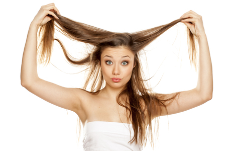 young blonde showing her long straight hair on white bckgroundの写真素材