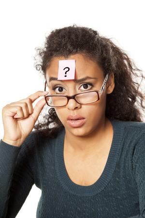 portrait of confused young dark-skinned woman with question mark on her forehead on a white backgroundの写真素材