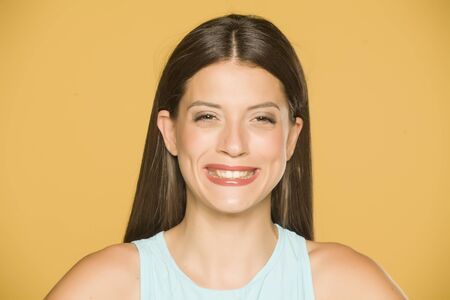 Portrait of happy beautiful young woman on yellow backgroundの写真素材