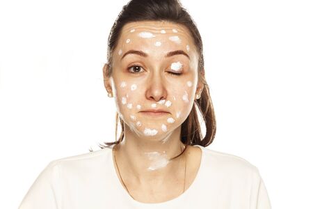 woman posing with face cream on white backgroundの写真素材