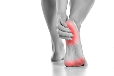 woman touching her painful heel on white backgroundの写真素材