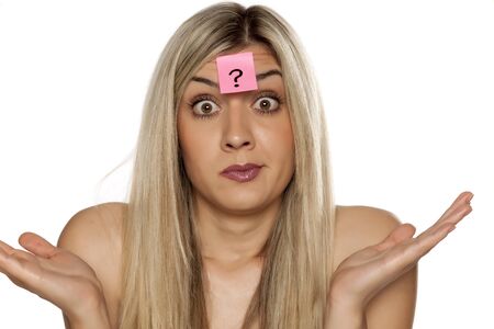 Portrait of young confused woman with question mark on her forehead on white backgroundの写真素材