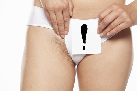 Young woman showing her pubic hair with exclamation mark on paper on white backgroundの写真素材