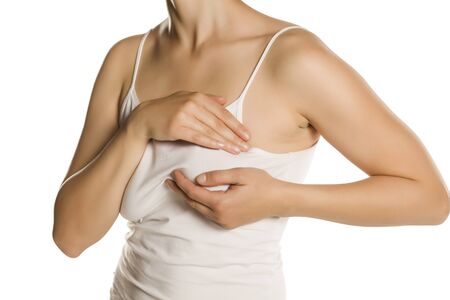 Young woman checking her breasts with her fingers on white backgroundの写真素材