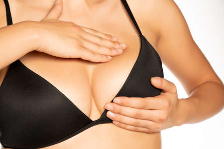 Woman checking her breasts with her fingers on white backgroundの写真素材