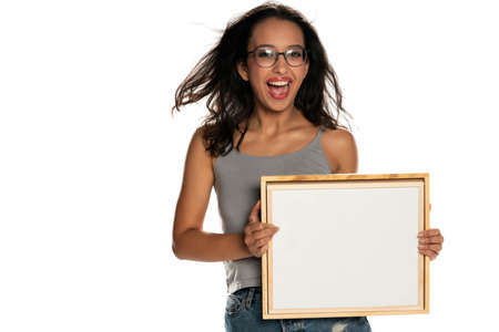 Happy dark skinned woman holding empty whiteboard on white backgroundの写真素材
