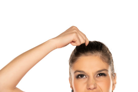 Half portrait of young nervous woman scratches her head on white background
