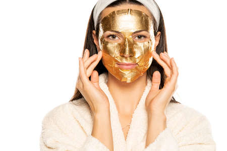 young woman posing with golden mask on her face on white backgroundの写真素材