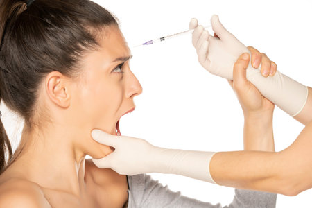 Portrait of a young scared woman on a faace filler injection procedure on white background
