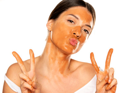 Young smiling woman with too dark liquid foundation on her face on white backgroundの写真素材