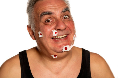 funny middle aged man with blood points with paper on his face on white backgroundの写真素材