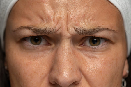 close up of a frowning woman with wrinkles between the eyebrows