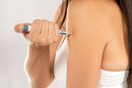 closeup of injecting an insulin injection in hand on a gray background