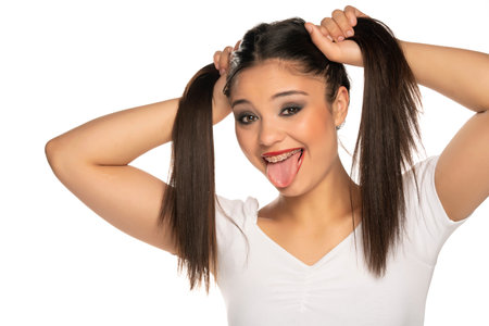 young funny woman holding her hair in two ponytails on a white background